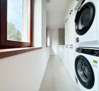 Practical laundry room in a 3-bedroom apartment with a washing machine and dryer on a white floor.