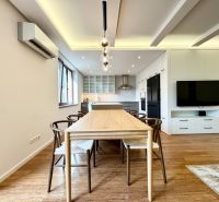 A kitchen in a 3-room apartment with lighting, wood-decor flooring, and a dining table.