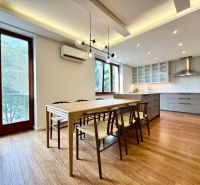 Kitchen in a 3-room apartment, wooden decor flooring, large windows, dining table.