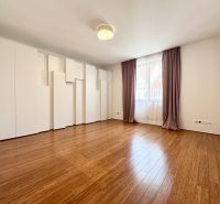 A spacious room in a 3-room apartment with wood-patterned flooring and built-in wardrobes.