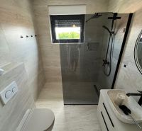 A bathroom in a 3-room apartment with a large shower and a wall-mounted toilet.