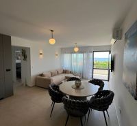 Living room of a 3-room apartment with a round table, sofa, and view.