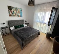 A bedroom with a bed, an art painting, and a wooden decor floor in a 3-room apartment.