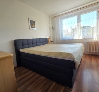 Bedroom with a large bed, wooden decor flooring, and a window in a 3-room apartment.