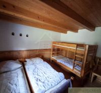 A room with two beds and a bunk bed, wooden decor on the walls and ceiling.