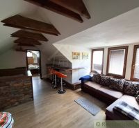 Attic interior with wood-decor flooring, a sofa set, and a bar counter.