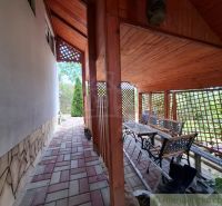A terrace by the cottage in Gbelce with paving and garden seating under a wooden roof.
