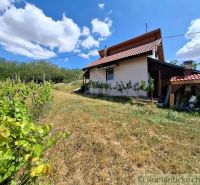 A cottage near Gbelce surrounded by vineyards and green landscape under a blue sky.
