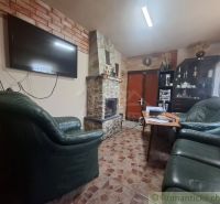 Stone fireplace and leather sofas in a cabin with a tile-style floor.