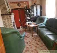 Interior of a cabin with a fireplace, leather sofa set, and a display case on a wooden-decor floor.