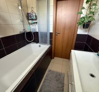 A bathroom in a 3-room apartment with a bathtub, sink, and tiles, suitable for comfort.