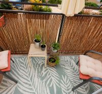 A balcony with flowers and chairs with cushions in a 3-room apartment.