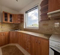 A kitchen with wooden decor, kitchen cabinets, appliances, and a window in a two-room apartment.