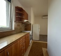 A kitchen in a 2-room apartment with a stone countertop and a window.