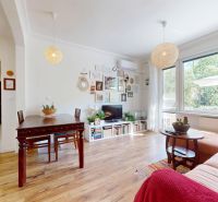 Living room in a 3-room apartment with a wooden decor floor, large window, and decorative elements.