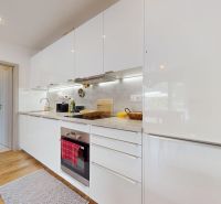 A kitchen with appliances, white cabinets, and a wood-patterned floor in a 3-room apartment.