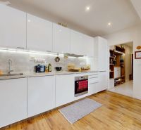 A kitchen in a 3-room apartment with a white kitchen unit and a wooden decor floor.