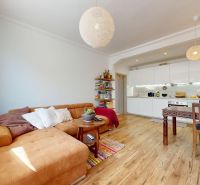 Living room with kitchen in a three-room apartment with a wooden decor floor.