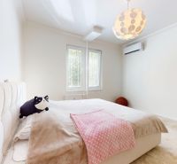 A bright bedroom with a large bed, two windows, and air conditioning in a 3-room apartment.