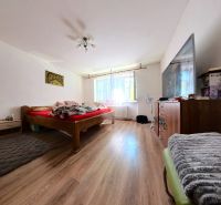 Bedroom in a family house with a bed, wardrobe, and wooden decor flooring.