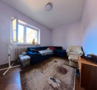 Living room in a family house with a blue sofa, an armchair, and a carpet on a floor with a wooden decor.