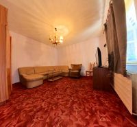 Living room in a family house with a corner sofa and a burgundy carpet.