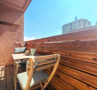 A balcony with wooden paneling and furniture in a 2-room apartment.