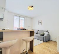 Living room in a two-room apartment with a wood-patterned floor and modern furnishings.