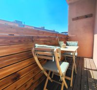 A balcony with wooden decor and garden furniture in a 2-room apartment.