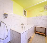 A bathroom with a bathtub and white tiles in a family house.