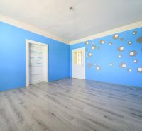 A room in a family house with blue walls, a pattern of circles, and a floor with a wooden decor.