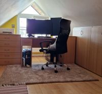 Attic office in a 2-room apartment with a wooden decor floor and a desk.