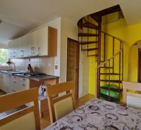 A kitchen in a 2-room apartment with a spiral staircase and light cabinets.