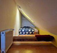 Attic room with a sloped ceiling, radiator, and floor with wooden decor.