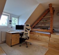 An attic office with a desk, chair, and wooden decor flooring in a 2-room apartment.