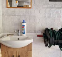 Bathroom in a 2-room apartment with a sink, mirror, and wall-mounted hose holder.