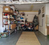 A garage full of stored items and a shelving system, next to a sink and a ladder.