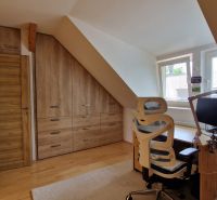 An attic space with wooden decor, a desk, and a chair in a 2-room apartment.