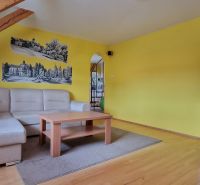 Living room with a sofa, wooden decor flooring, and yellow walls in a two-room apartment.