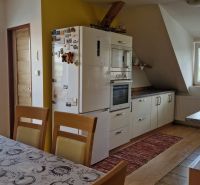 A kitchen in a 2-room apartment with a wooden decor floor and a dining table.