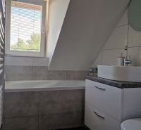 A bathroom in a 2-room apartment with a bathtub, a sink, and hexagonal tiles.