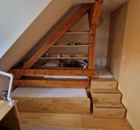 Attic room with wooden elements, a bed, and a desk in a 2-room apartment.