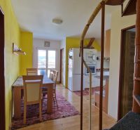 Bright kitchen with a dining table in a 2-room apartment with wood-patterned flooring.