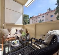 Balcony of a 2-room apartment with cozy seating and greenery.