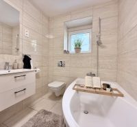 Bathroom with a bathtub and a sink in a 2-room apartment, beige tiles.