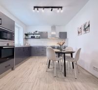 Modern kitchen in a two-room apartment with a wooden decor floor and a dining table.