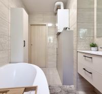 A bathroom in a 2-room apartment with a bathtub, furniture, and tiles decorated with geometric patterns.