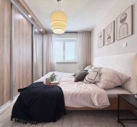 A bedroom in a two-room apartment with a wooden decor floor, a large built-in wardrobe, and wall decorations.