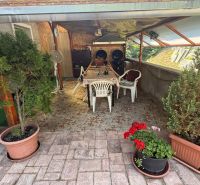 Terrace of a family house in Zvolen with wooden decor, a table, and potted plants.