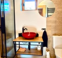 A bathroom in a family house, with a wooden decor floor, a window, and a mirror.